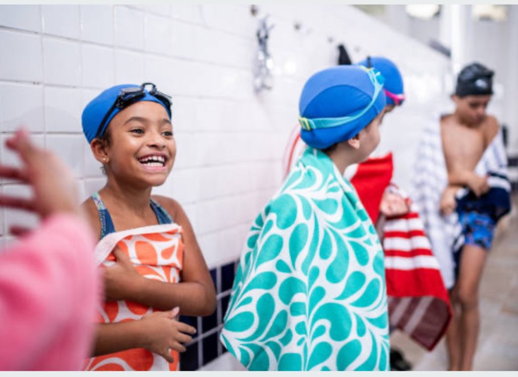 Happy kids wrapped in towels, drying off after a fun swim.